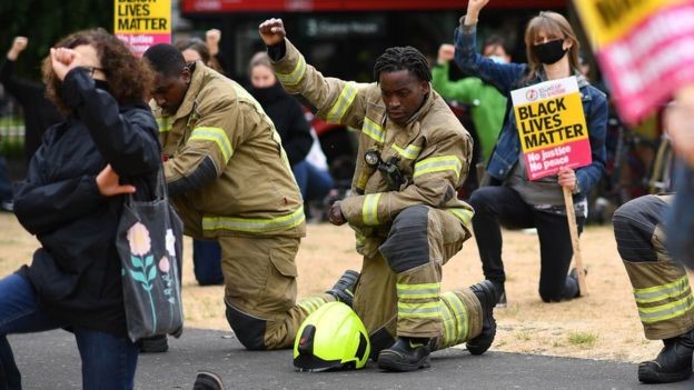 Black protesters kneeled in front of police