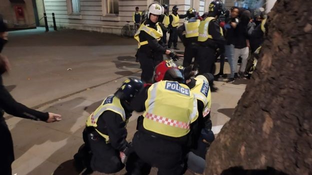 A firefighter in uniform kneels during the protest